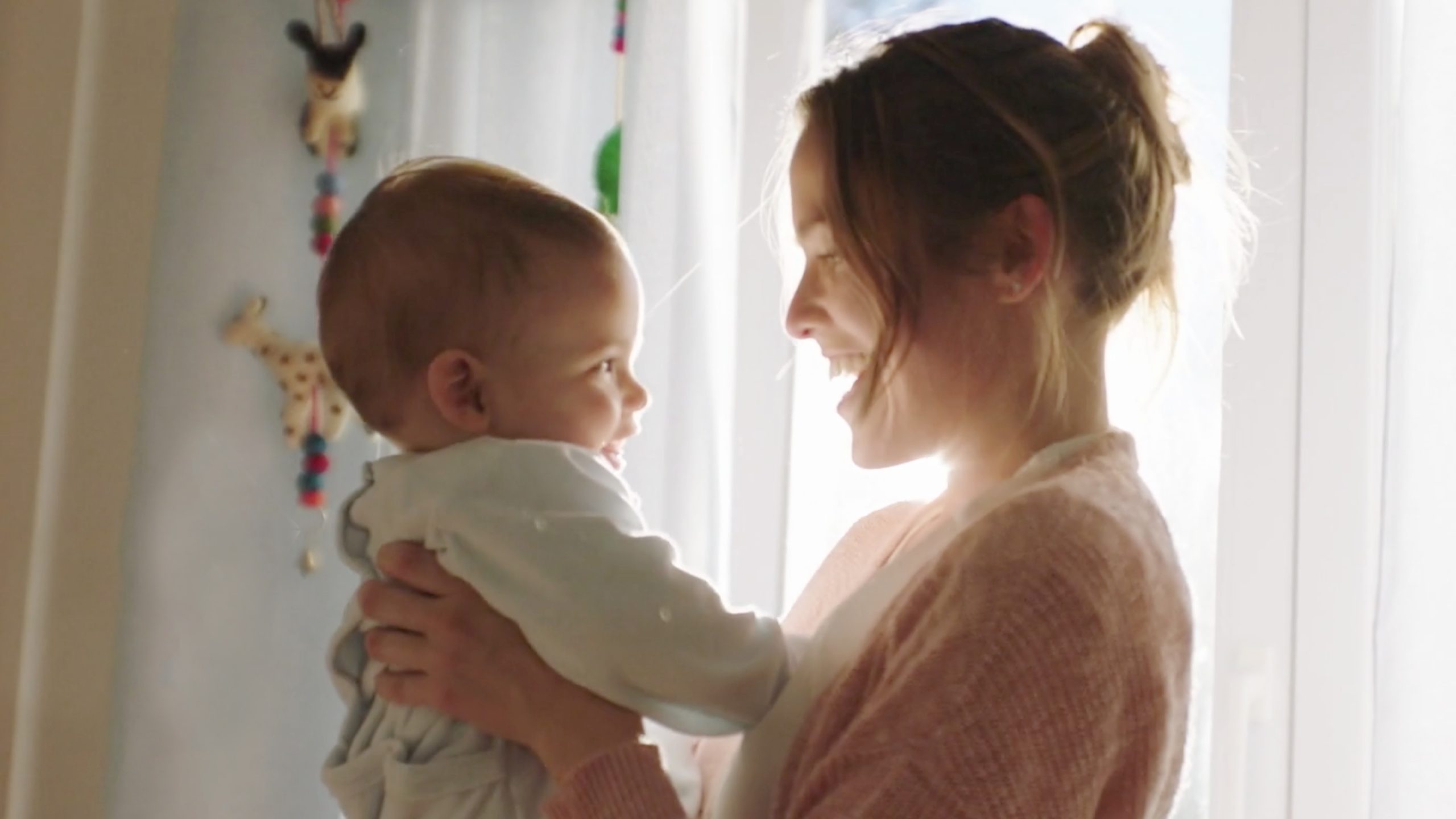 Photograph of a mother and baby in a natural, bright setting, representing tenderness and closeness.